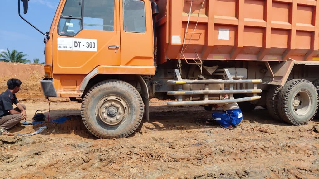 Teknisi melakukan pemasangan AC di kolong truck